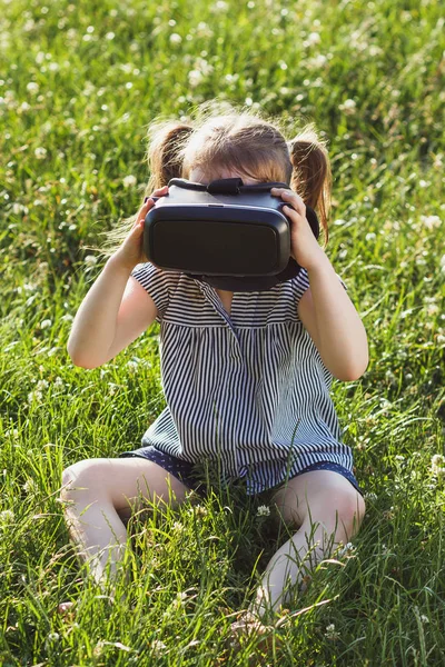 Menina joga jogo com óculos de realidade virtual ao ar livre — Fotografia de Stock