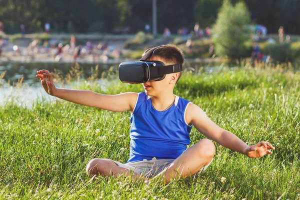 Menino joga jogo com óculos de realidade virtual ao ar livre — Fotografia de Stock