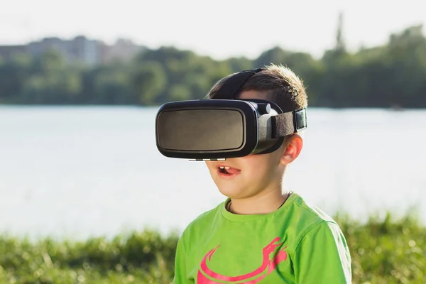 Menino joga jogo com óculos de realidade virtual ao ar livre — Fotografia de Stock