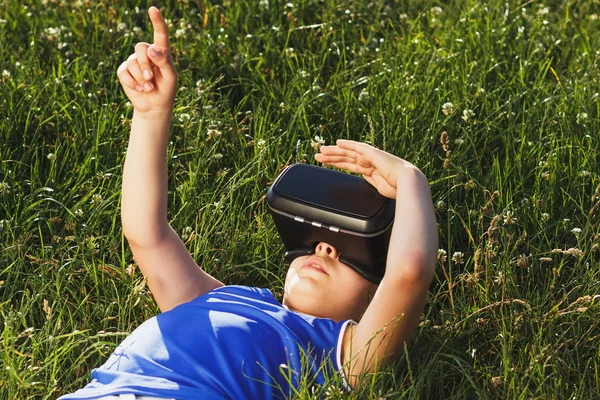 Jongen speelt een spel met een vr bril buitenshuis — Stockfoto