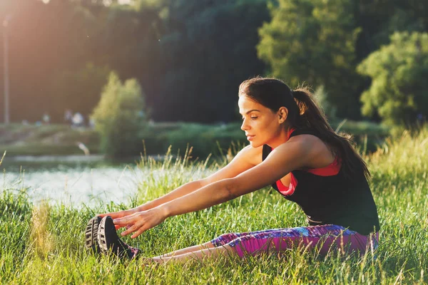 Спортивная женщина на берегу озер делает спортивные упражнения на закате — стоковое фото