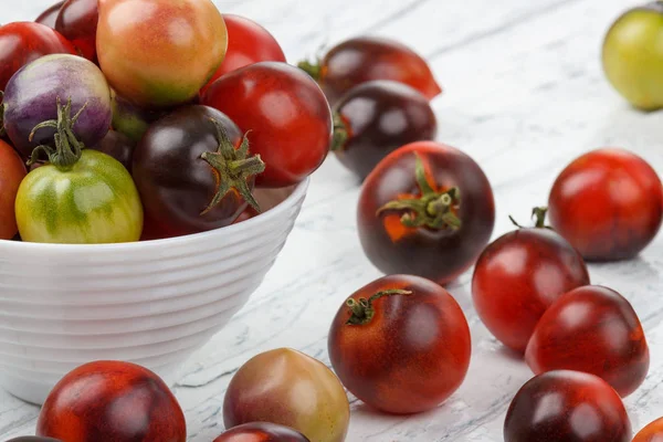 Verschillende tomaten in de kom op de witte houten achtergrond — Stockfoto