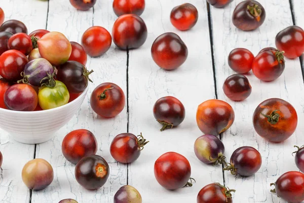 Diferentes tomates en el tazón sobre el fondo de madera blanca — Foto de Stock