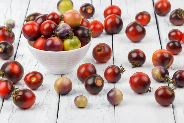 Diferentes tomates en el tazón sobre el fondo de madera blanca — Foto de Stock