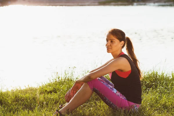 Mujer deportiva en la costa de los lagos hace ejercicios deportivos en la puesta del sol — Foto de Stock