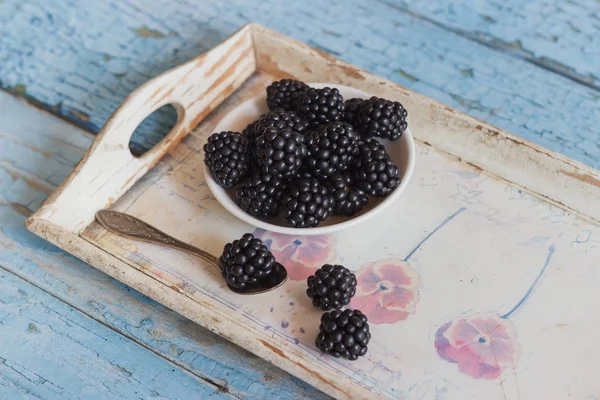 BlackBerry ahşap tepsi üzerinde bir kaşık beyaz kase