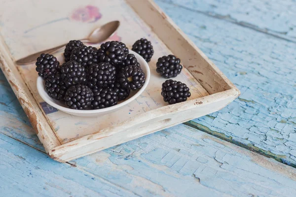 Blackberry in the white bowl with a spoon on the wooden tray — Stock Photo, Image