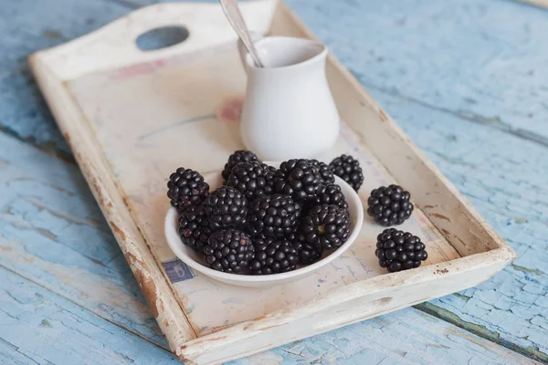 Blackberry in the white bowl with a spoon on the wooden tray — Stock Photo, Image