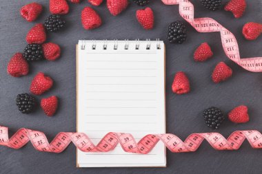 Kırmızı Ahududu, böğürtlen, mezura ve siyah arduvaz taş zemin üzerine defter