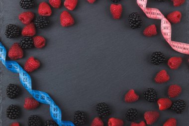 Kırmızı Ahududu, böğürtlen ve siyah arduvaz taş zemin üzerine şerit metre