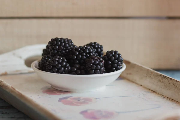 Blackberry in the white bowl on the wooden tray — Stock Photo, Image