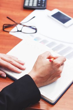 Bir kalem, not defteri ve birkaç grafikler ile el