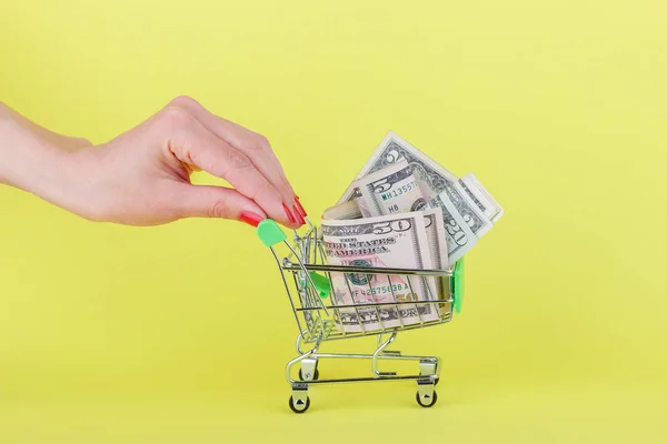 Amerikanische Dollar im Einkaufswagen, gelber Hintergrund — Stockfoto