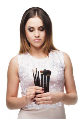 Çekici gülümseyen kadın elinde makyaj fırça seti ile