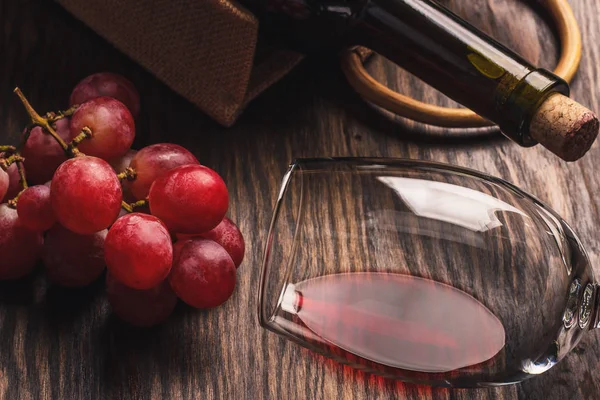 Glas mit Wein, einer Flasche und einem Bund reifer Trauben, Holzhintergrund — Stockfoto