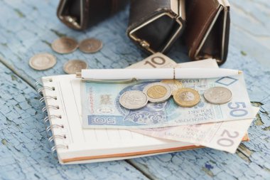 Küçük cüzdan ve ahşap arka plan üstünde defter ile Polonya Zlotisi