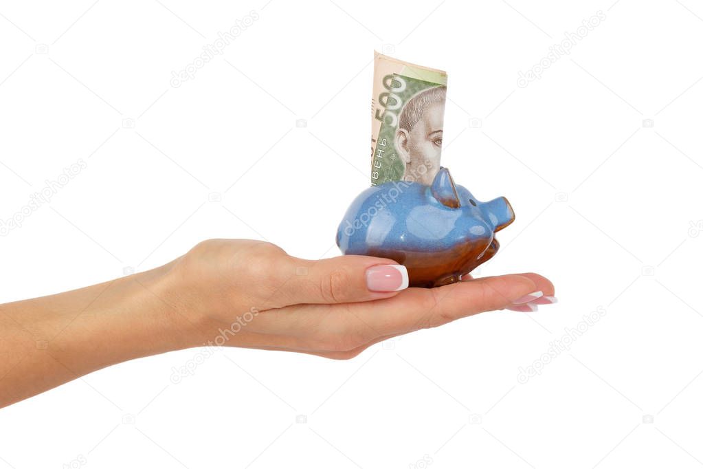 Woman's hand holds piggy bank with banknote of five hundred hryvnias