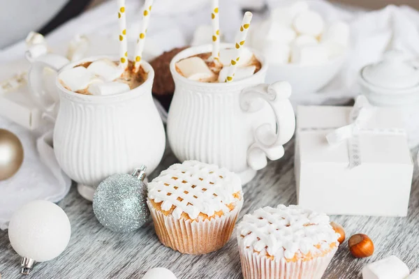 Koppar med kakao och marshmallow, cupcakes och annat julpynt, trä bakgrund — Stockfoto