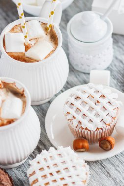 Su bardağı kakao ve şekerleme, kek ve farklı süslemeler, ahşap arka plan ile