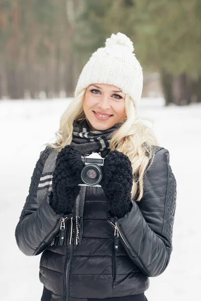 Mujer con una vieja cámara en las manos, bosque de invierno — Foto de Stock