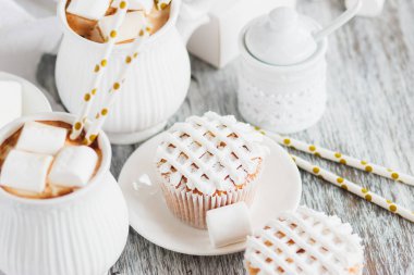 Su bardağı kakao ve şekerleme, kek ve farklı süslemeler, ahşap arka plan ile