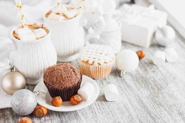 Koppar med kakao och marshmallow, cupcakes och annat julpynt, trä bakgrund — Stockfoto