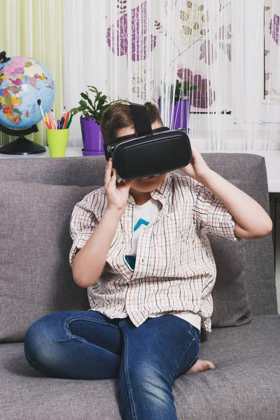 Menino brinca com óculos de realidade virtual, dentro de casa. Dispositivo de realidade virtual digital — Fotografia de Stock