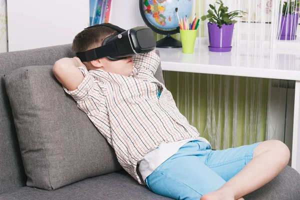 Menino está assistindo vídeo com óculos de realidade virtual, dentro de casa. Dispositivo de realidade virtual digital — Fotografia de Stock