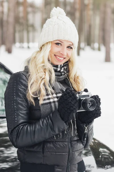 Mujer con una vieja cámara en las manos, bosque de invierno — Foto de Stock