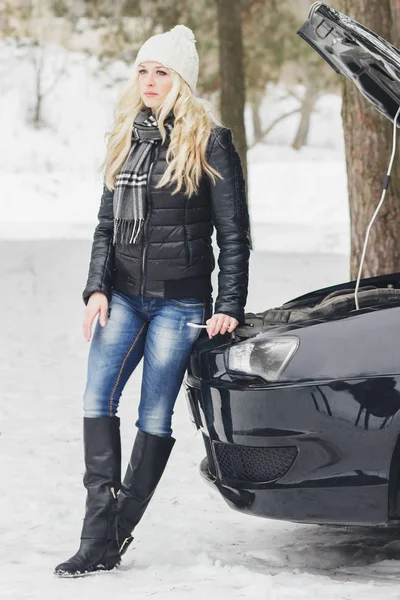 Woman driver near a black car, car problem, wintertime