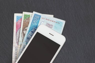 Polonya Zlotisi ve siyah arduvaz taş zemin üzerine bir telefon