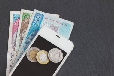 Polonya Zlotisi ve siyah arduvaz taş zemin üzerine bir telefon