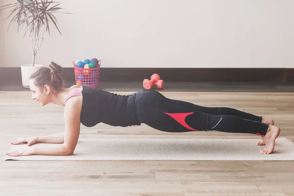 Vrouw maakt de yoga oefening op de mat, binnenshuis — Stockfoto