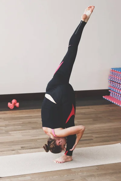 Mujer hace el ejercicio de yoga en la esterilla, en interiores — Foto de Stock