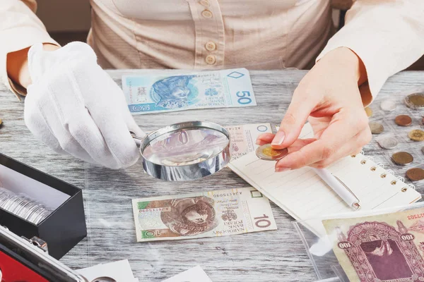 Mujer con lupa, monedas y billetes — Foto de Stock