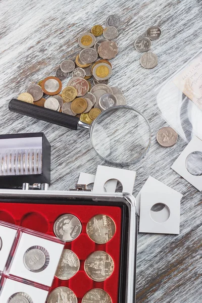 Diferentes monedas de colección con una lupa —  Fotos de Stock