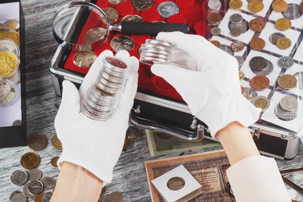 Mains dans les gants avec des pièces de collection dans les boîtes — Photo