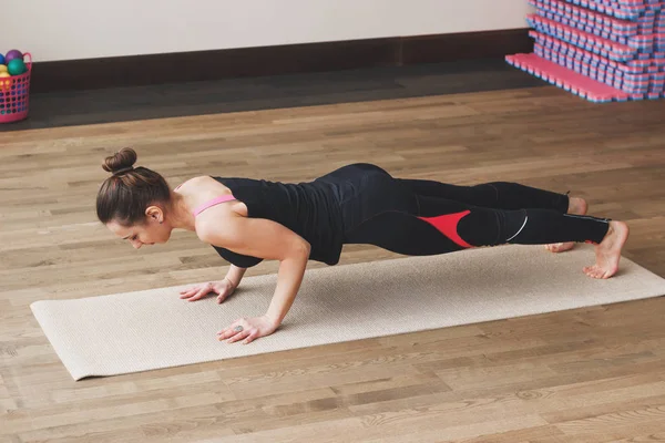 Vrouw maakt de yoga oefening op de mat, binnenshuis — Stockfoto