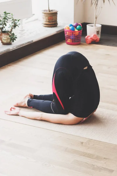 Mujer hace el ejercicio de yoga en la esterilla, en interiores — Foto de Stock