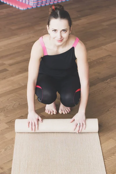 Mujer hace el ejercicio de yoga en la esterilla, en interiores — Foto de Stock