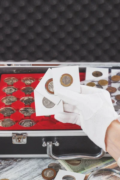 Mano en el guante sostiene volteretas con monedas de colección — Foto de Stock