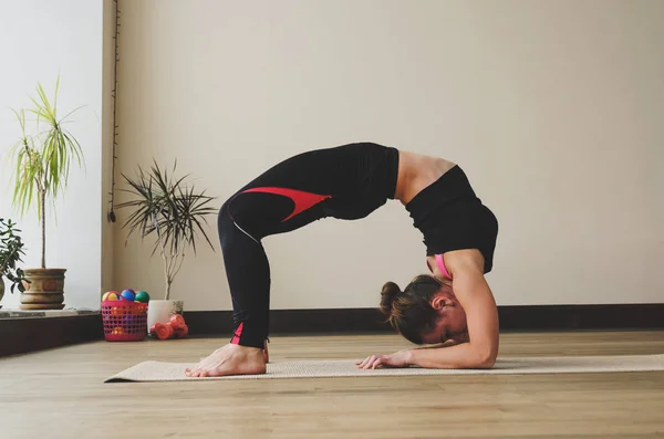 Mujer hace el ejercicio de yoga en la esterilla, en interiores — Foto de Stock