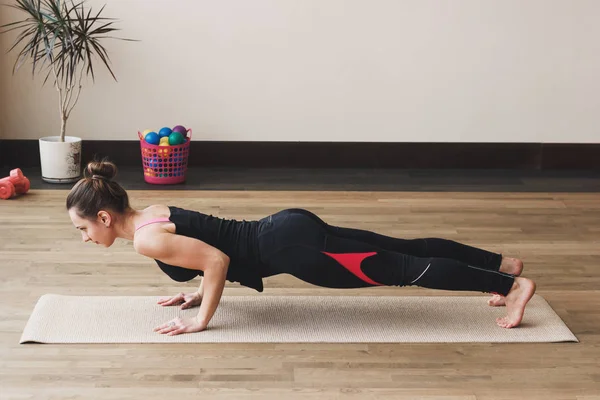 Vrouw maakt de yoga oefening op de mat, binnenshuis — Stockfoto