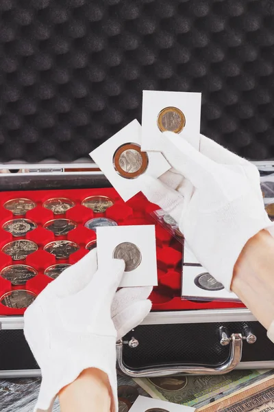 Las manos en los guantes sostienen volteretas con monedas de colección —  Fotos de Stock