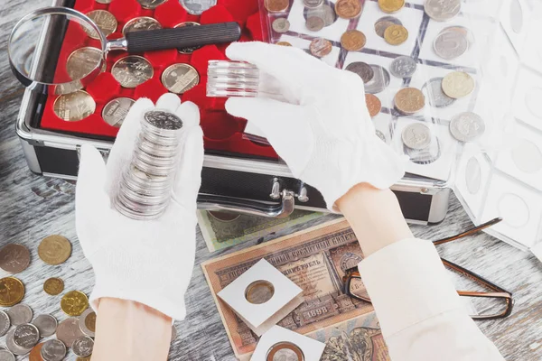 Manos en los guantes blancos con diferentes monedas de colección en las cajas —  Fotos de Stock