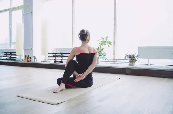 Mujer hace el ejercicio de yoga en la esterilla, en interiores — Foto de Stock