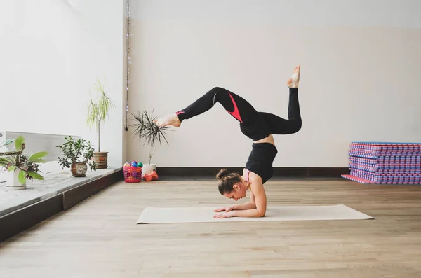 Mujer hace el ejercicio de yoga en la esterilla, en interiores — Foto de Stock