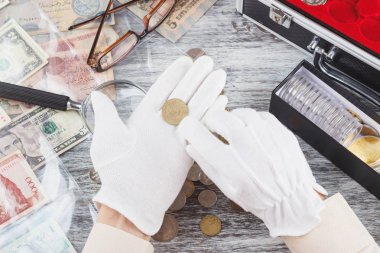 Eldivenleri elinde altın toplayıcı sikke tut