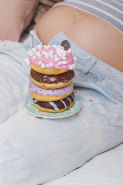 Plaka üzerinde farklı çörek ile hamile kadın