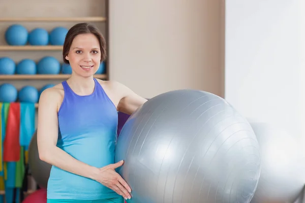 Mujer deportiva embarazada con una pelota de ejercicio en las manos — Foto de Stock